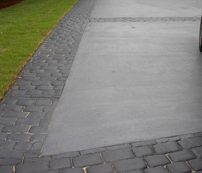 Gray textured driveway bordered by stamped concrete edging.