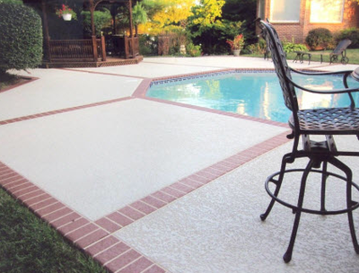 Concrete pool deck with decorative stamped brick design as the border.