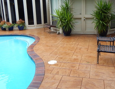 Pretty patio and pool deck made out of stamped concrete with two-tone border.